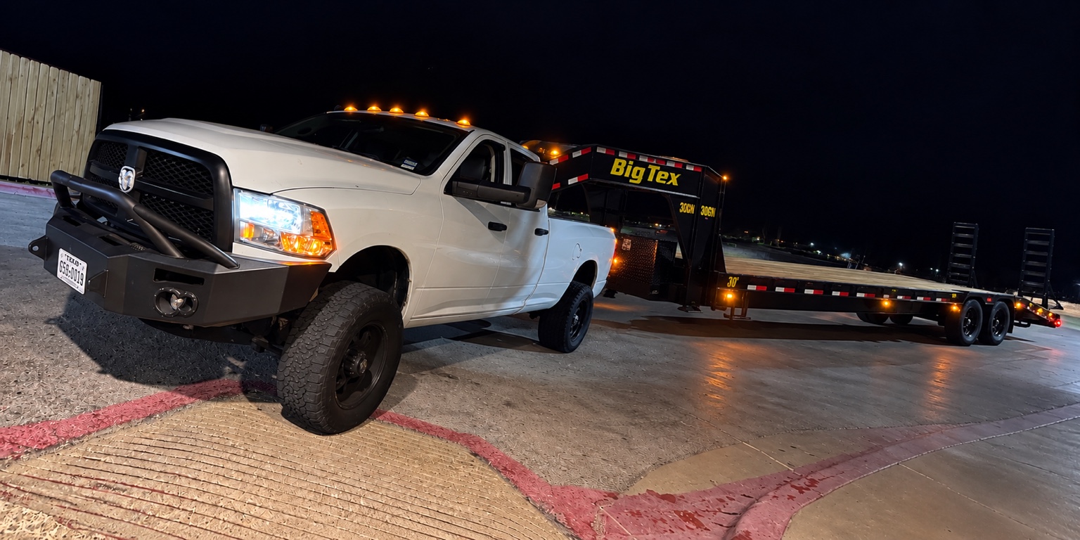 RADZ white Ram truck with its Big Tex gooseneck flatbed trailer at night